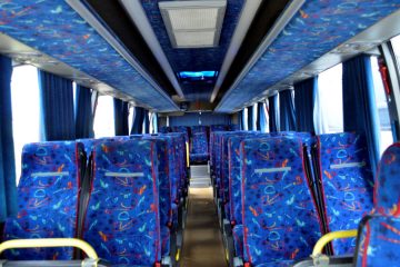 Interior de autocar cu scaune albastre și culoar central