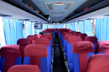Interior autocar cu scaune albastre și roșii, perdele albastre