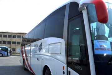 Autocar alb cu dungi roșii văzut din lateral față