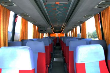 Interior autocar cu scaune gri și roșii, perdele portocalii