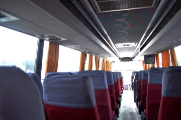 Interior de autocar cu scaune roșii și perdele portocalii