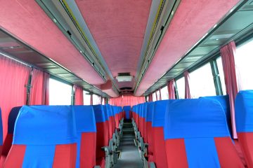 Interior autocar cu scaune roșii și albastre, perdele roz