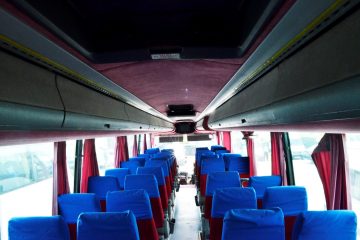 Interior autocar cu scaune albastre și perdele roșii