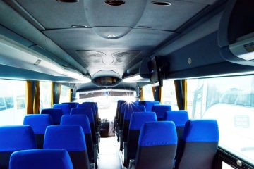 Interior autocar cu scaune albastre și ecran pe tavan
