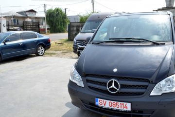 Microbuz negru văzut din față și autoturism albastru